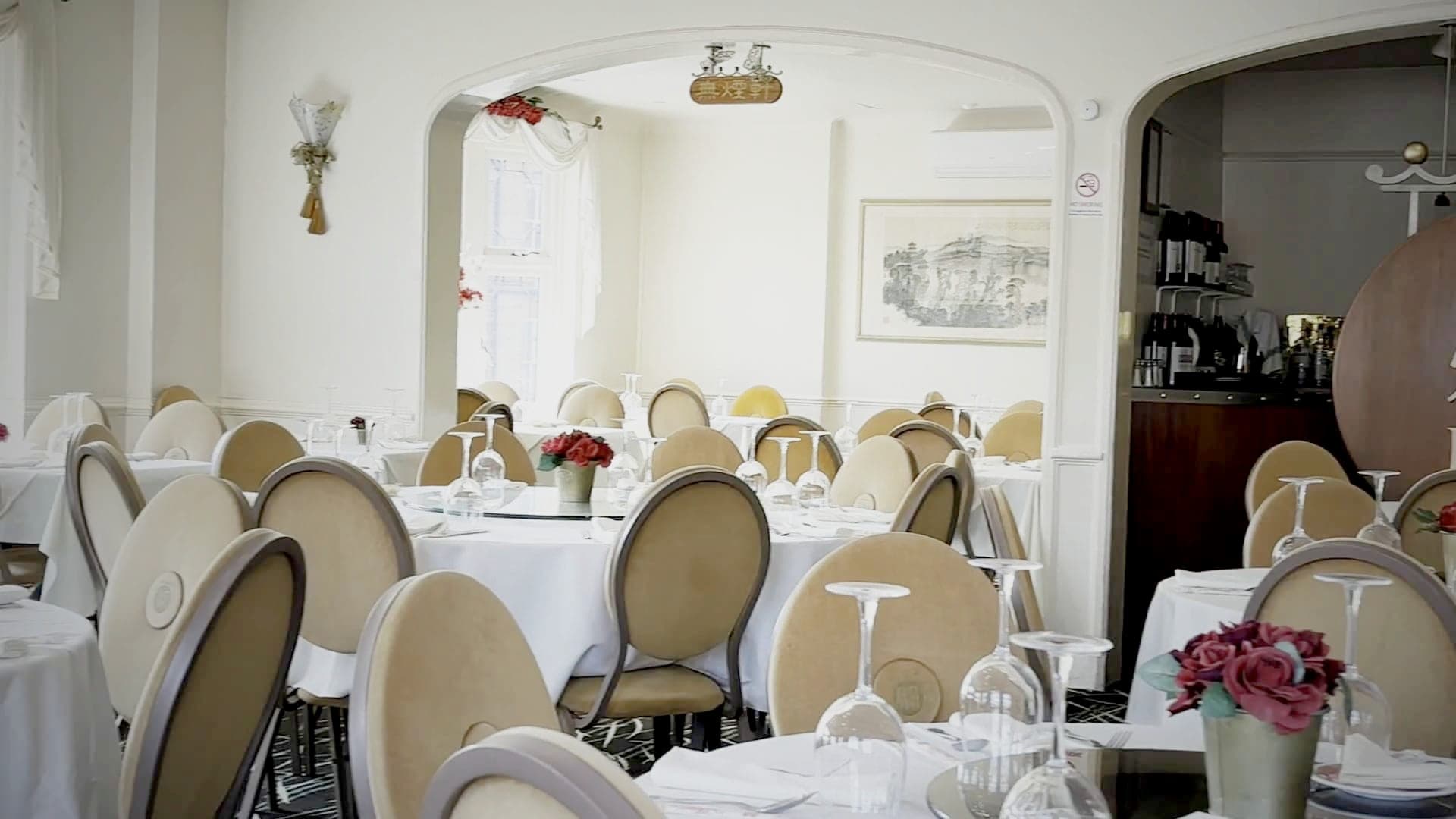 The dining room seen through the archway, round tables laid and waiting